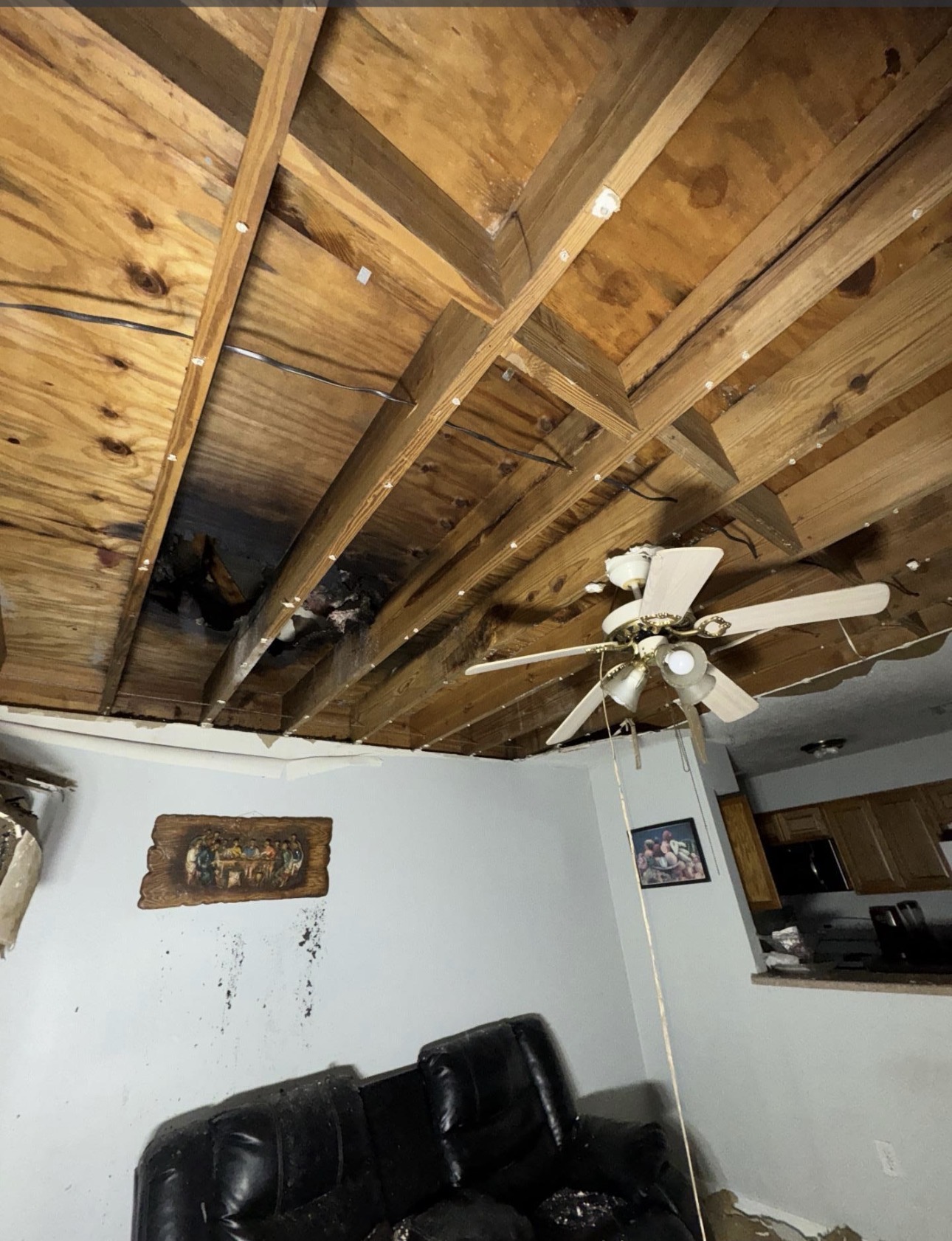 Fire-damaged ceiling with exposed wood framing during cleanup